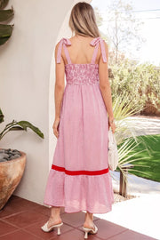 Maxi dress with pink and white stripes, smocked bodice, bow knot straps, and red trim.