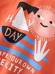 Coral cotton toddler t-shirt with "Happy Day" graphic and smiling sun.