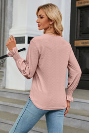 Blush pink textured V-neck blouse with smocked cuffs and lace trim detail.