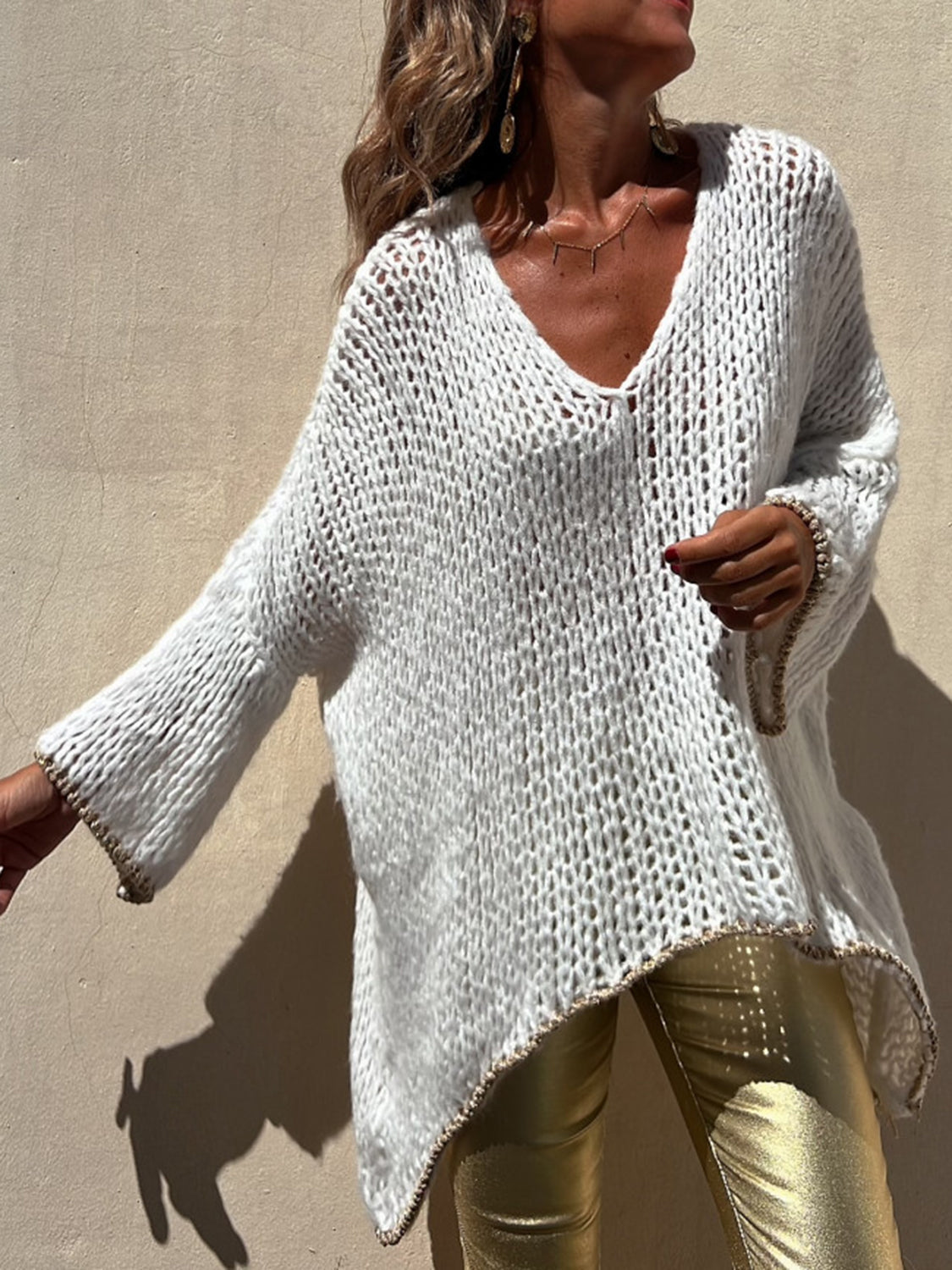 White open knit sweater with asymmetric hem and beaded trim detail.