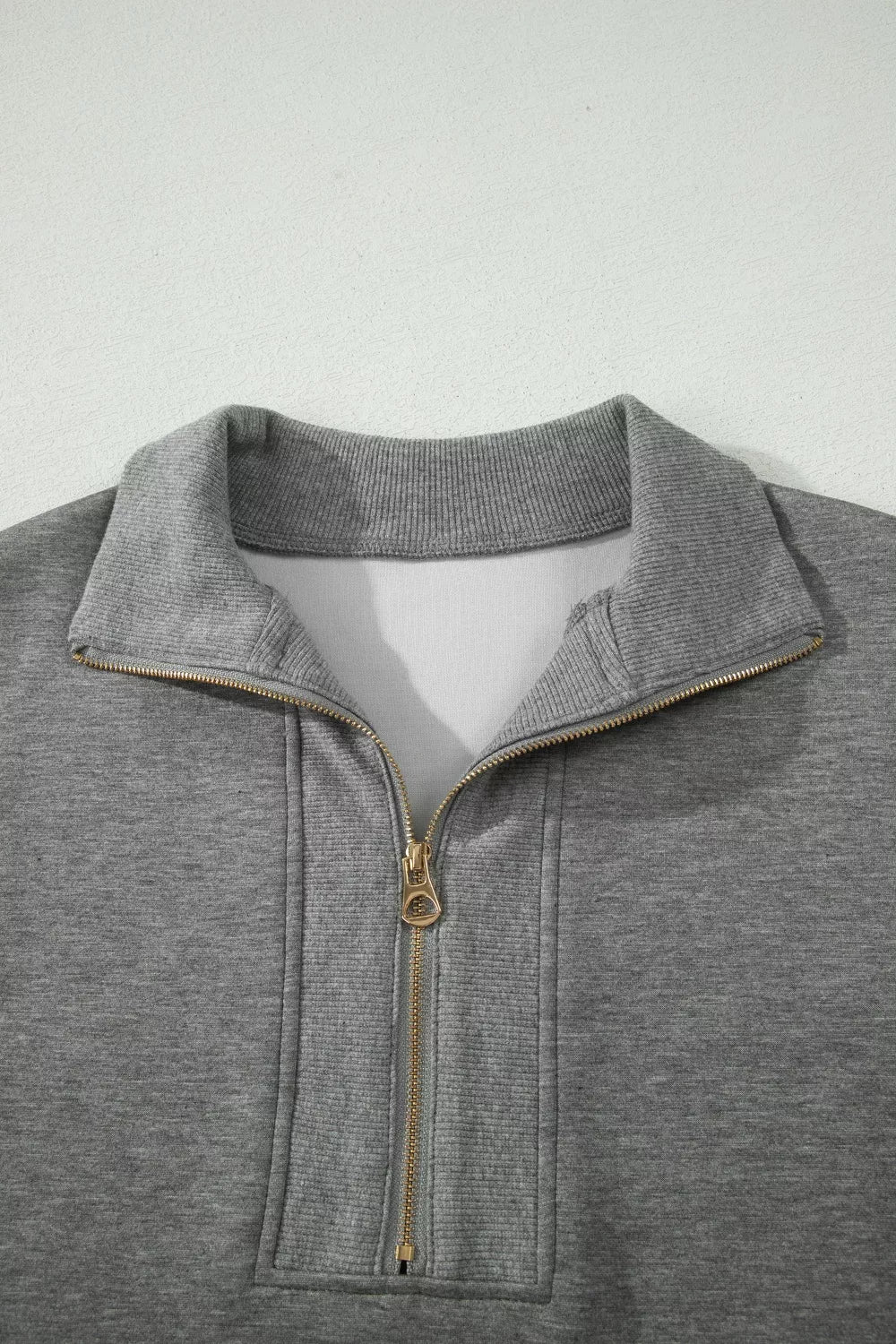 Chic dark gray half-zip polo sweatshirt with gold zipper detail and ribbed collar.