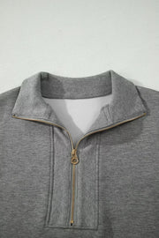 Chic dark gray half-zip polo sweatshirt with gold zipper detail and ribbed collar.