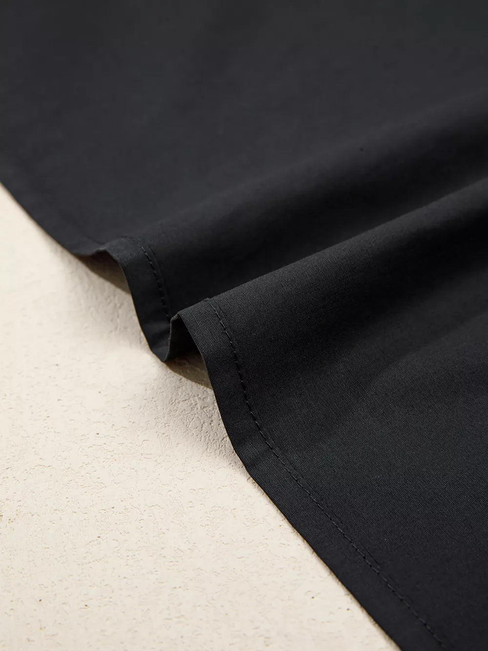 Black maternity overshirt detail showing fabric texture and stitching.