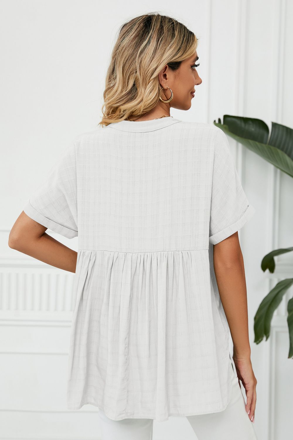 Gathered back v-neck linen blouse in white with short sleeves and a babydoll cut.