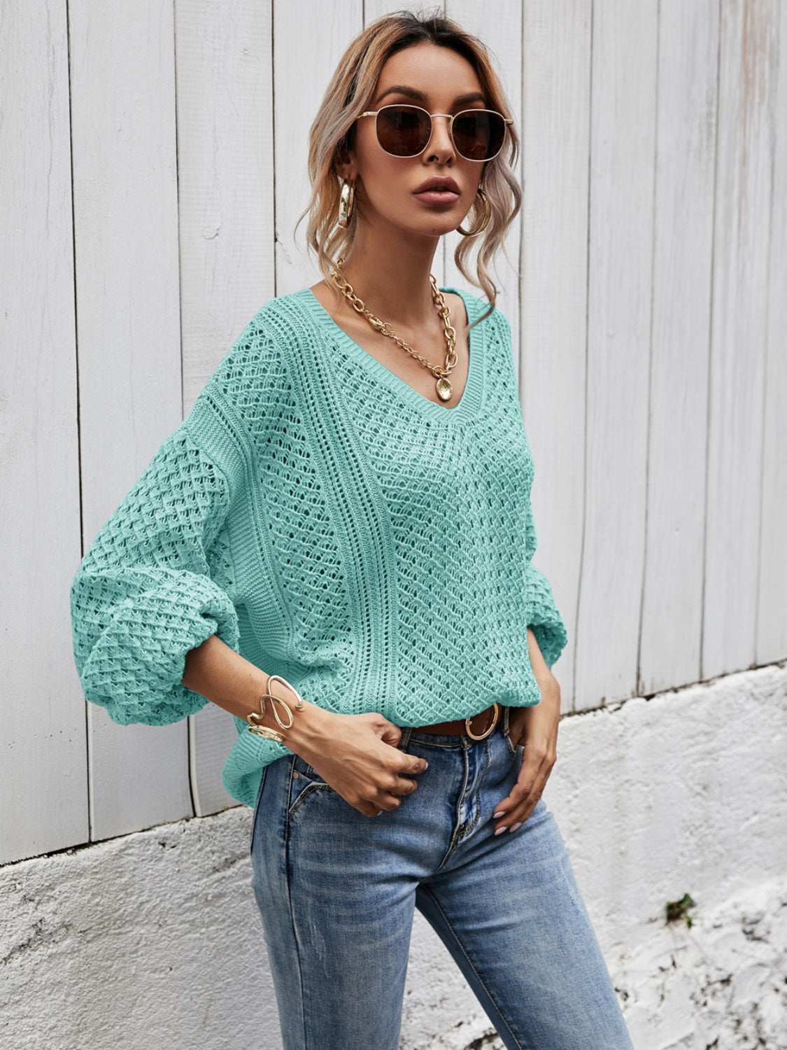 Teal open-knit sweater with balloon sleeves and V-neck, styled with jeans.