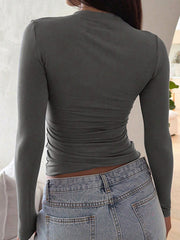 Gray long sleeve slim fit t-shirt with ruched sides, paired with light wash jeans.