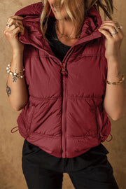 Burgundy quilted hooded puffer vest with drawcord hem and zipper pockets.