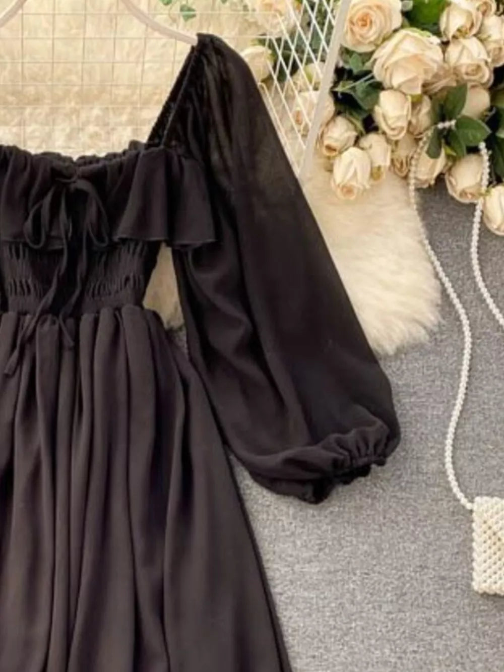 Black A-line maternity dress with square neck, ruffled trim, tie detail, and balloon sleeves.