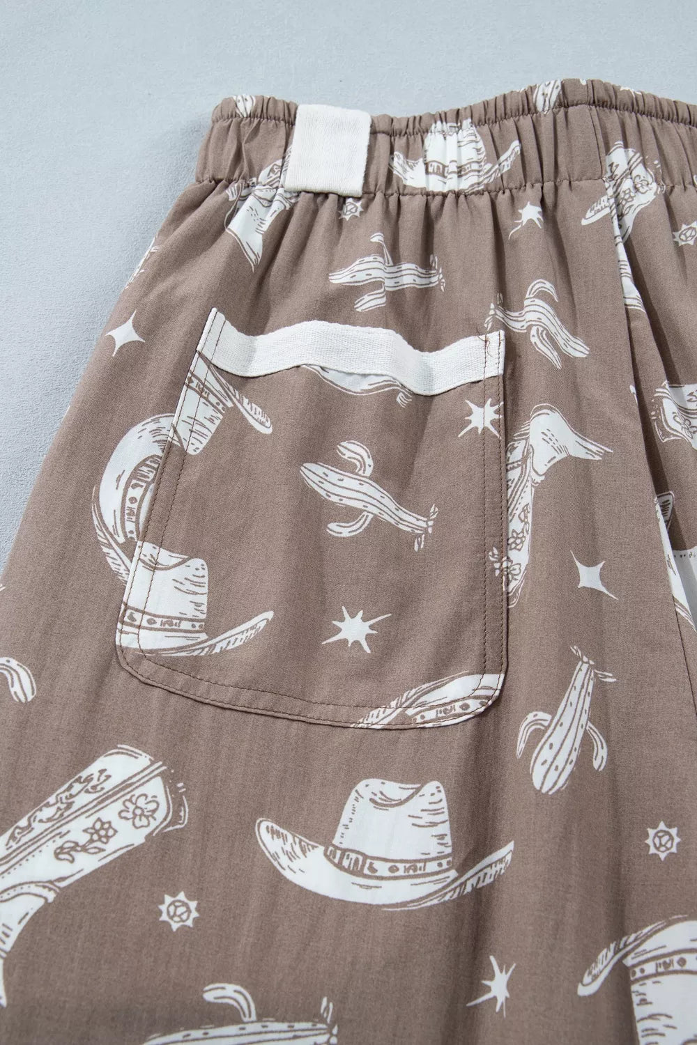 Brown cotton joggers with white western print, featuring cactuses and cowboy hats.