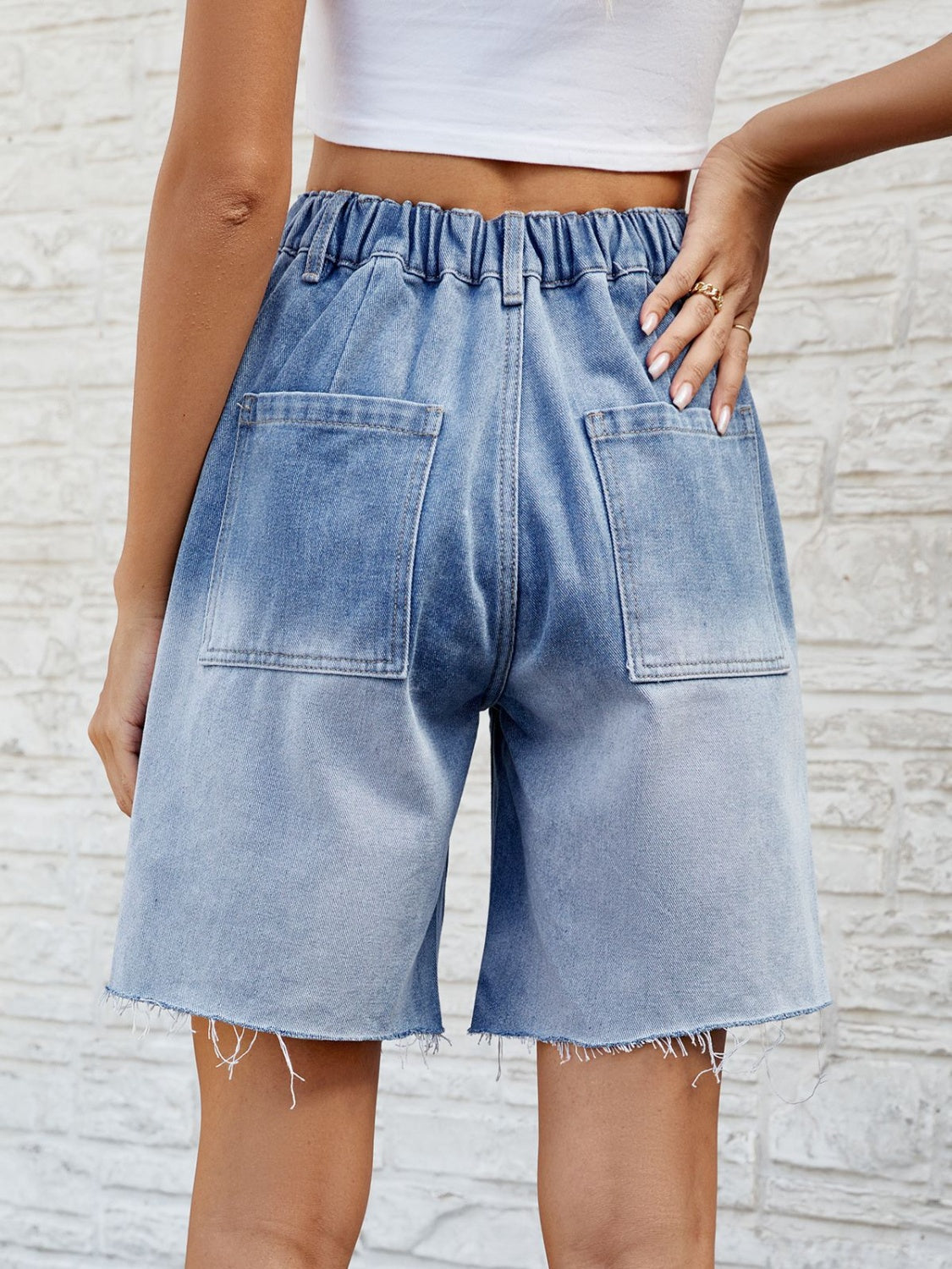 Light blue faded denim carpenter shorts with raw hem and elastic waistband.