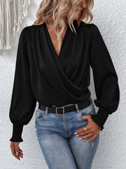Black ruched surplice blouse with long balloon sleeves and smocked cuffs.