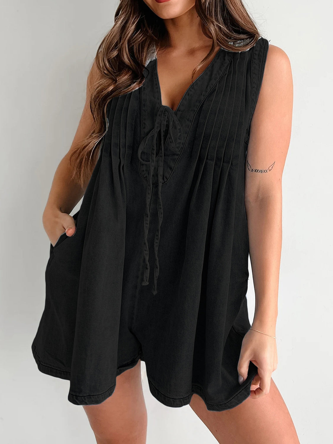 Black denim playsuit with V-neck tie front, sleeveless, A-line cut and pockets.