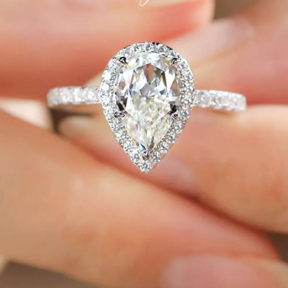 Elegant Moissanite Teardrop Ring in Sterling Silver with a halo of brilliant stones.