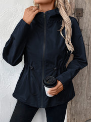 Navy utility jacket with cinched waistline, zipper, and hood.