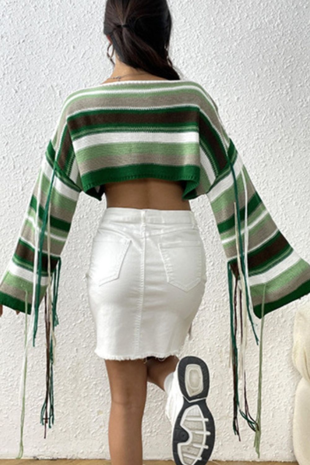 Cropped knit sweater with multicolor stripes and fringe details on sleeves.