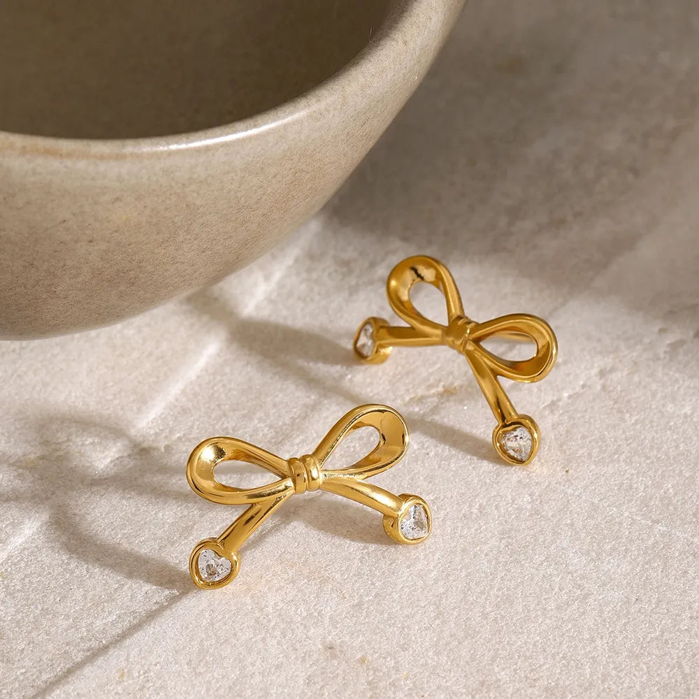 Gold cubic zirconia bow stud earrings with heart-shaped stones