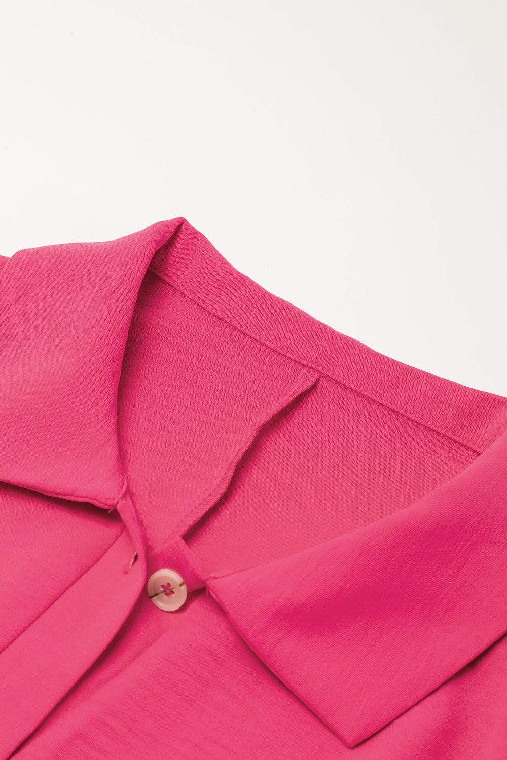 Oversized shirt romper in hot pink with a buttoned collar detail.