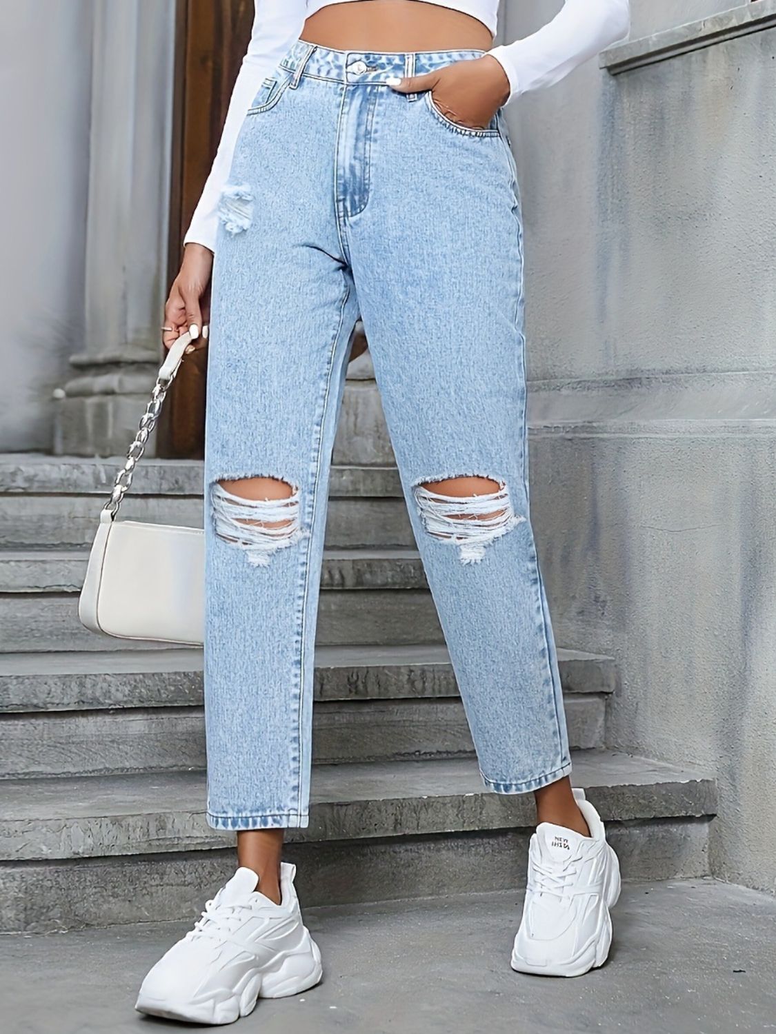 Light wash distressed boyfriend jeans with ripped knees and a bow detail.