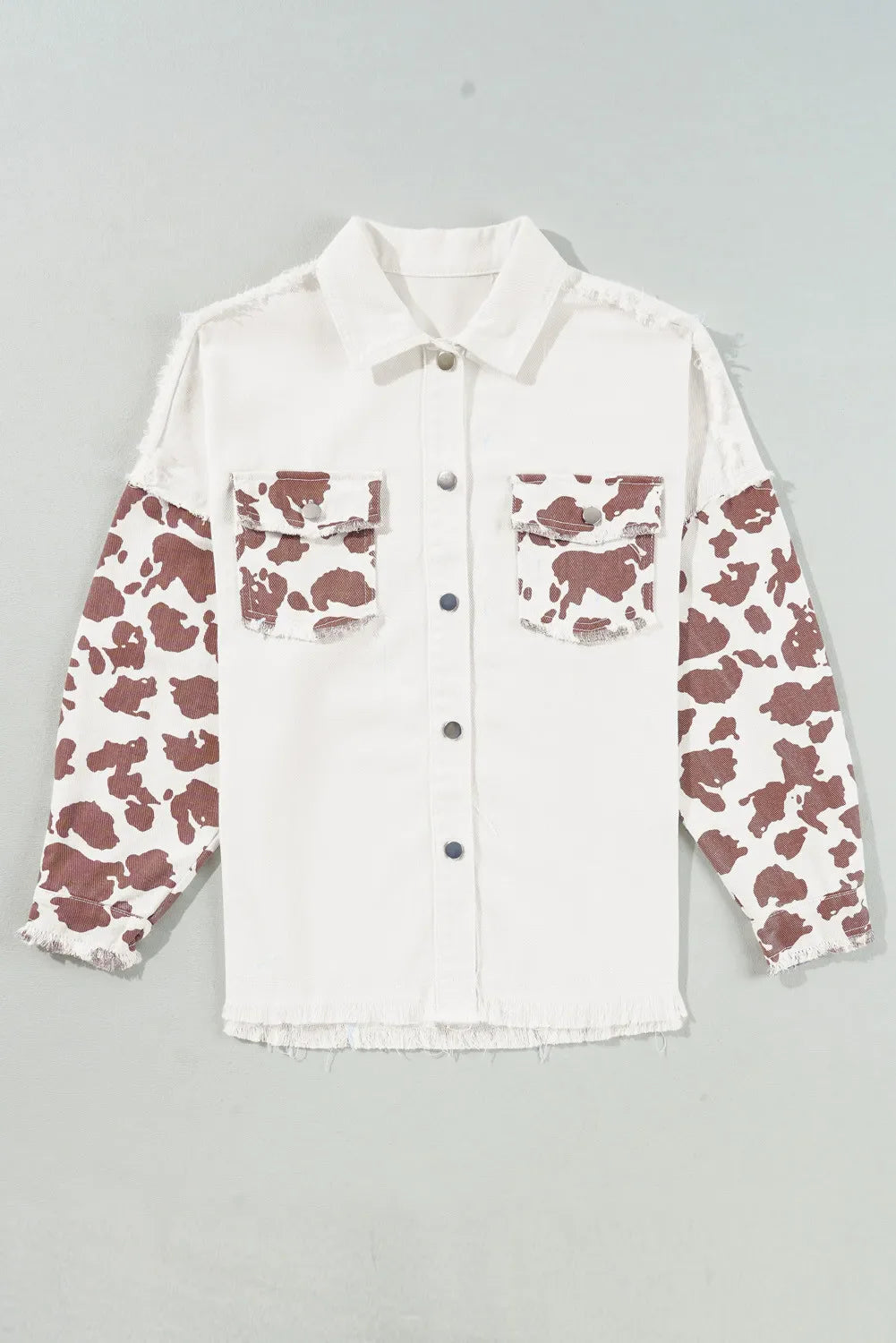 White cotton shacket with cow print sleeves and frayed edges.