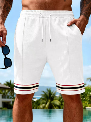 White textured knit drawstring shorts with pockets and striped cuffs.