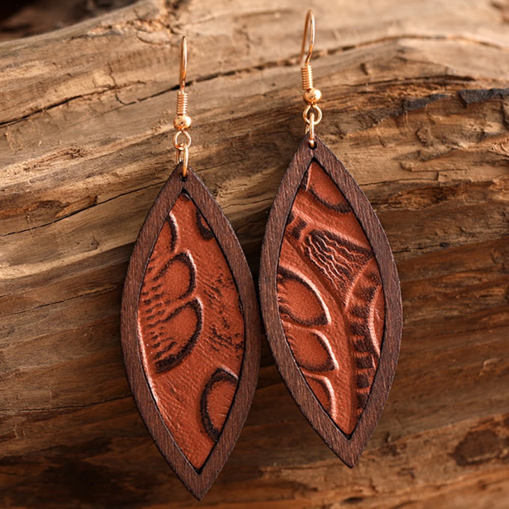 Tooled leather and wood drop earrings with a leaf pattern in brown.