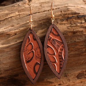 Tooled leather and wood drop earrings with a leaf pattern in brown.