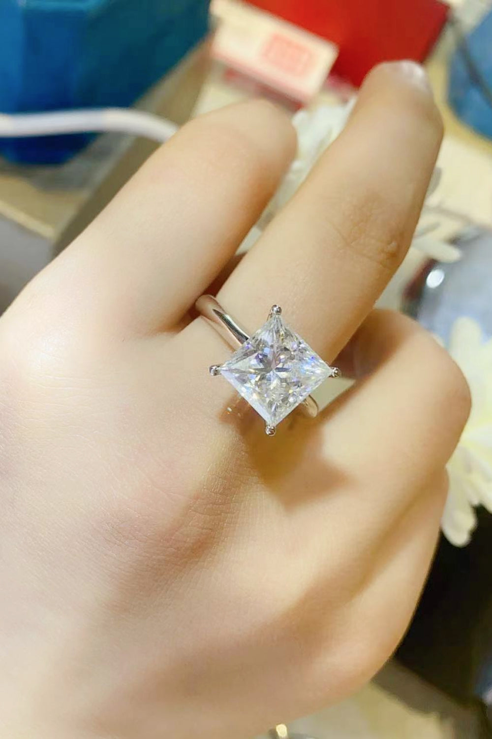 Silver ring with a bright princess-cut solitaire diamond on a hand.
