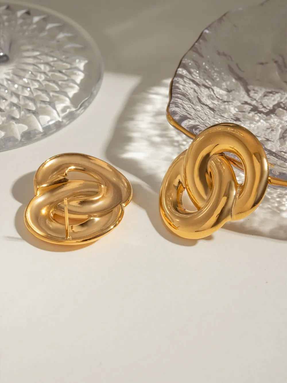 Interlocking gold statement earrings with a bold, casual design.