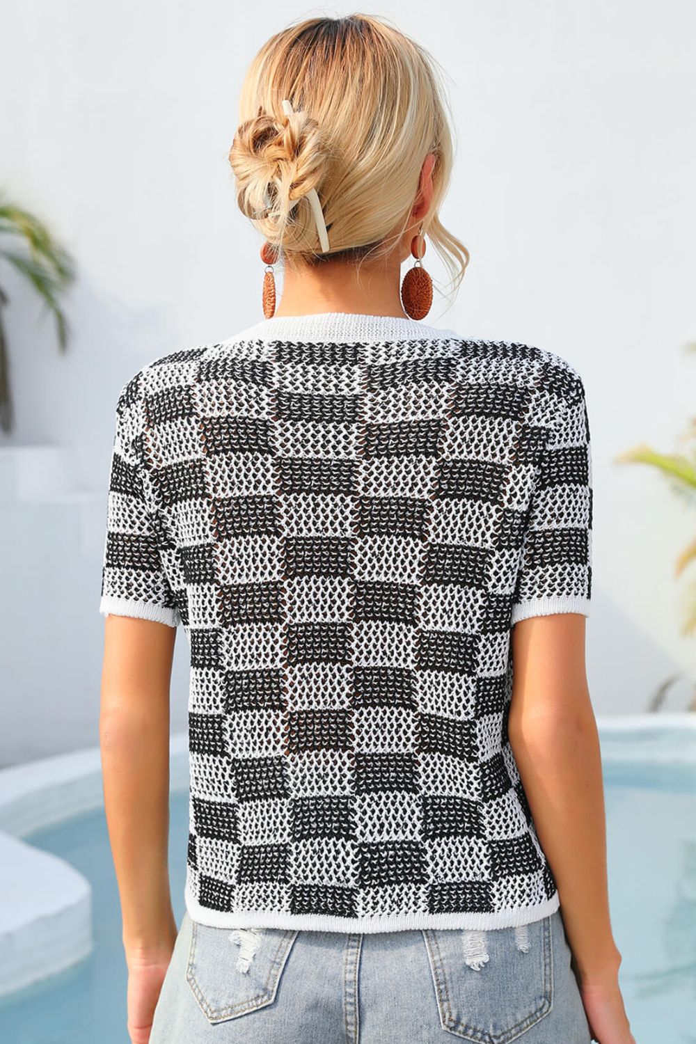 Checkerboard knit crewneck top in black and white with short sleeves.