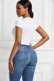 White crew neck bodysuit with short sleeves, paired with blue denim jeans.