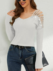 White ribbed knit blouse with cold shoulder cutouts and sequin embellishments.