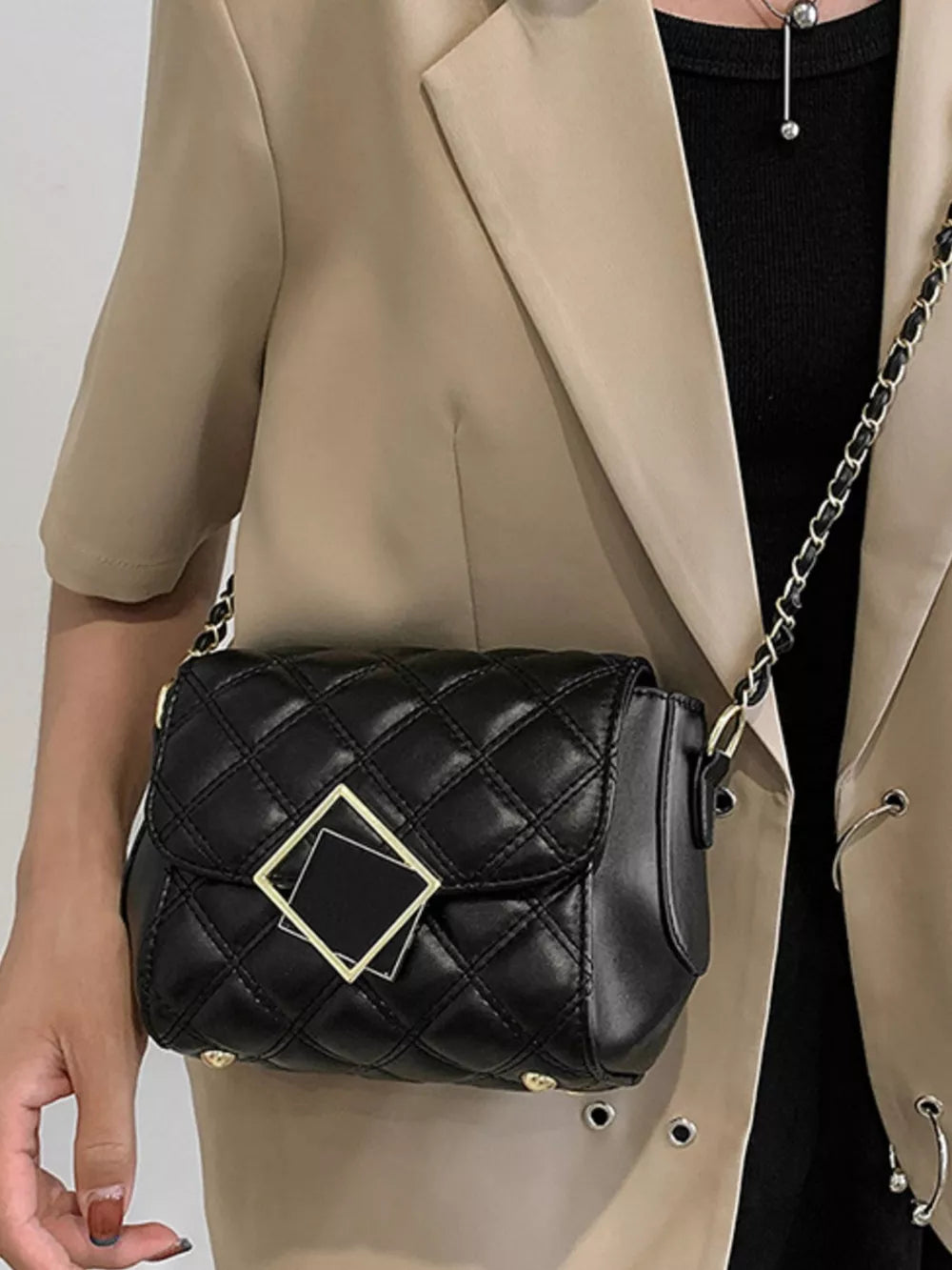 Black quilted crossbody bag with gold square detail and chain strap