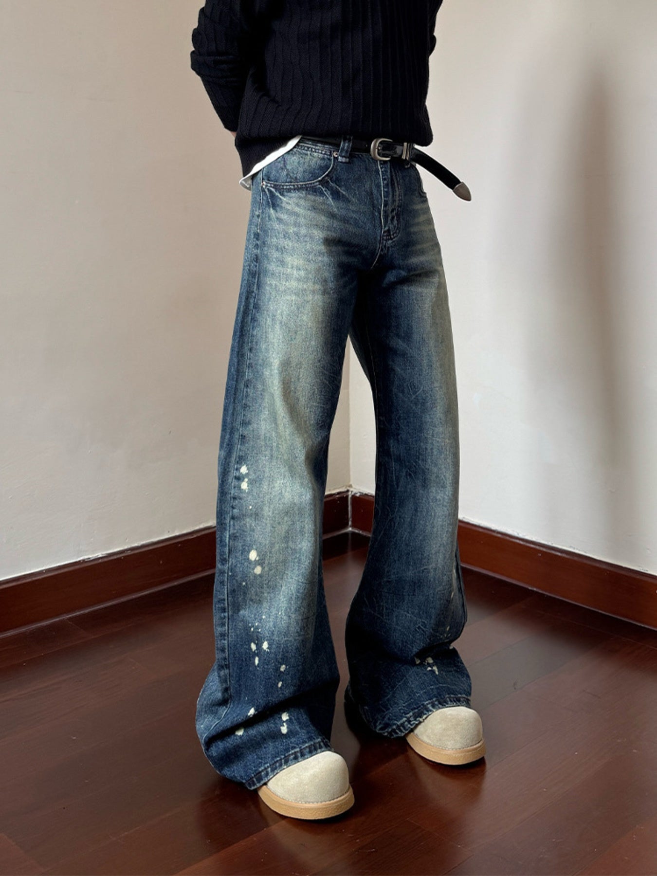 Men's blue vintage wash wide leg jeans with paint splatters and distressed details.