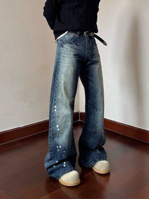 Men's blue vintage wash wide leg jeans with paint splatters and distressed details.