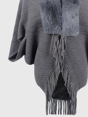 Textured knit poncho in charcoal with faux fur collar and fringe detail.