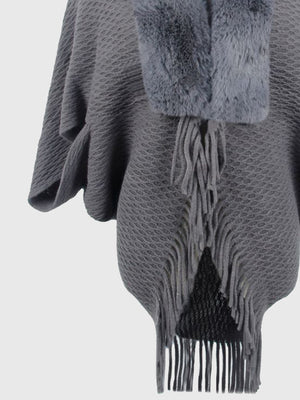 Textured knit poncho in charcoal with faux fur collar and fringe detail.