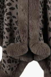 Leopard print cape with faux fur trim and pom poms in beige.