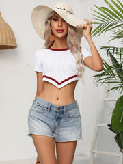 White knit crop top with chevron hemline and short sleeves, styled with denim shorts.