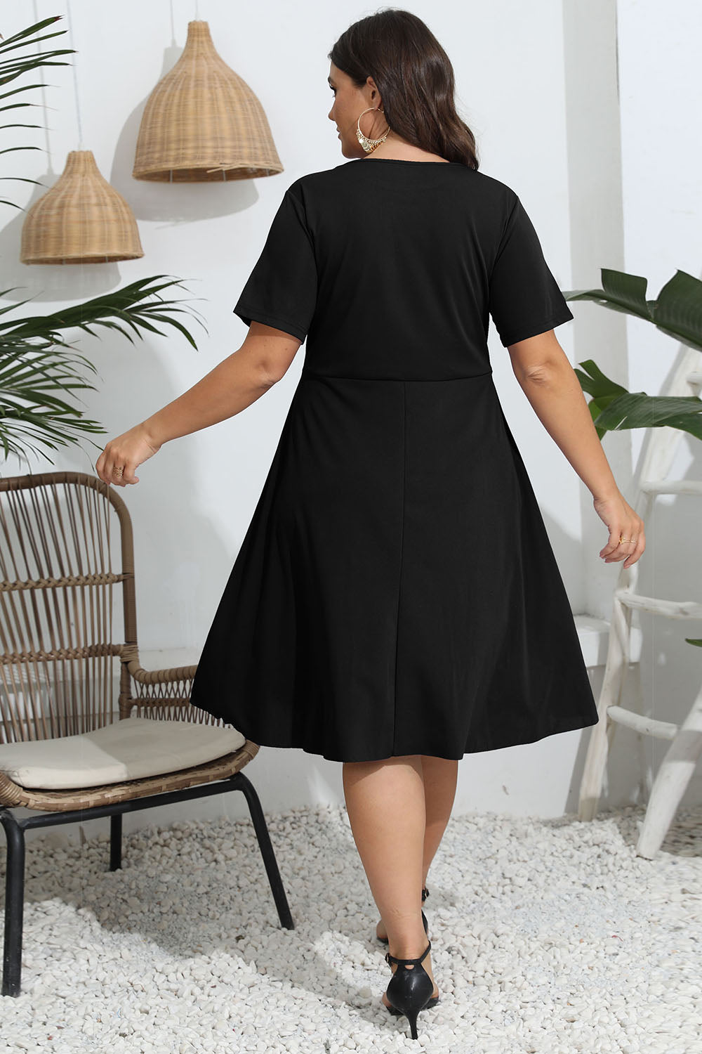 Black midi dress with short sleeves and a flared skirt, featuring laser cutouts.