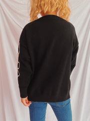 Black acrylic knit sweater with cream floral outline detail on sleeve