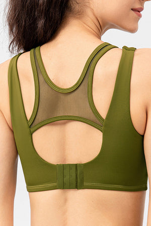 Mesh inset performance bra top in Matcha Green with cutout back and adjustable hook-and-eye closure.