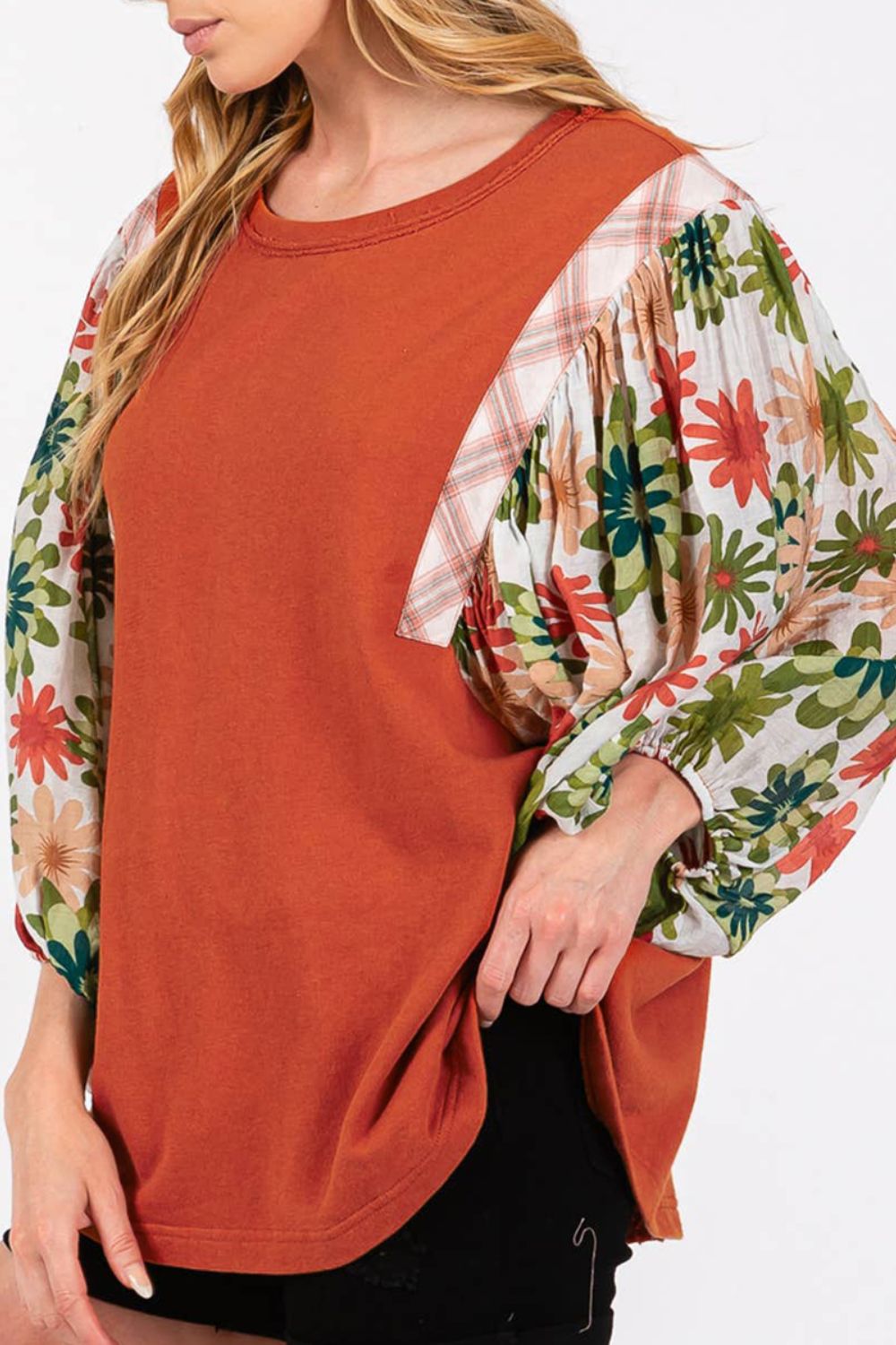 Orange-red blouse with floral patchwork balloon sleeves and plaid accents.
