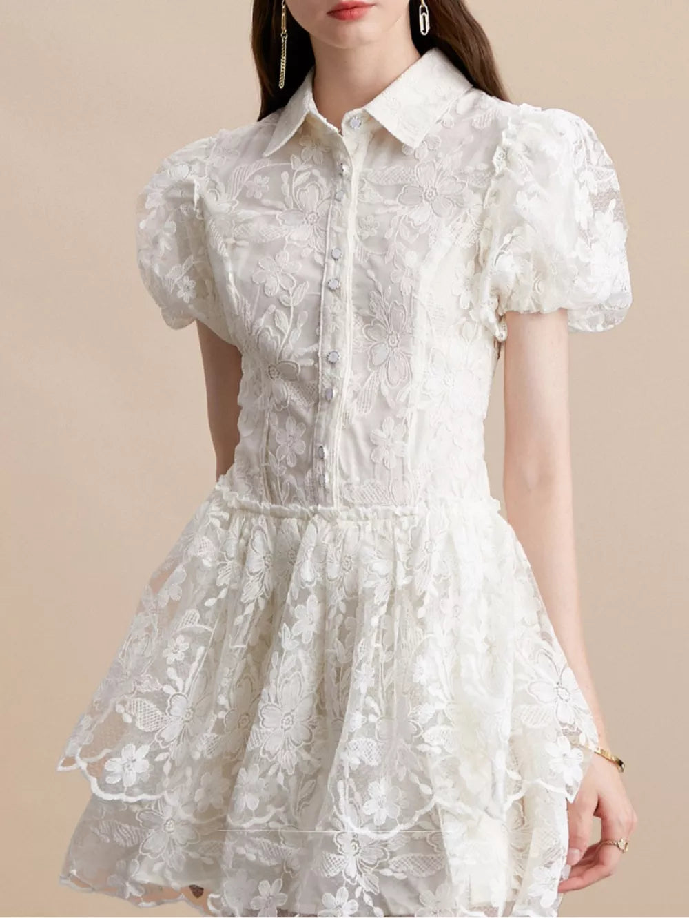 White lace mini dress with puff sleeves, button front, and tiered skirt.