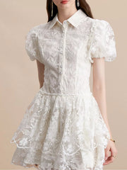 White lace mini dress with puff sleeves, button front, and tiered skirt.