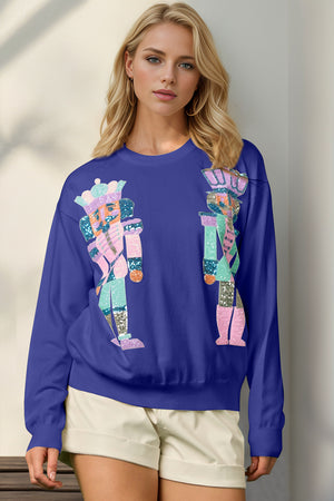 Royal blue crewneck sweater with colorful nutcracker appliqué, 100% polyester.