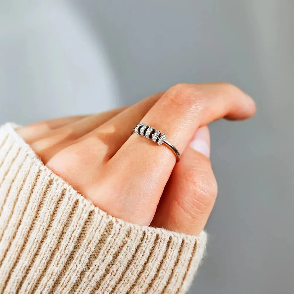 Sterling silver pavé band ring with rotating beads on a finger.