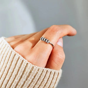 Sterling silver pavé band ring with rotating beads on a finger.