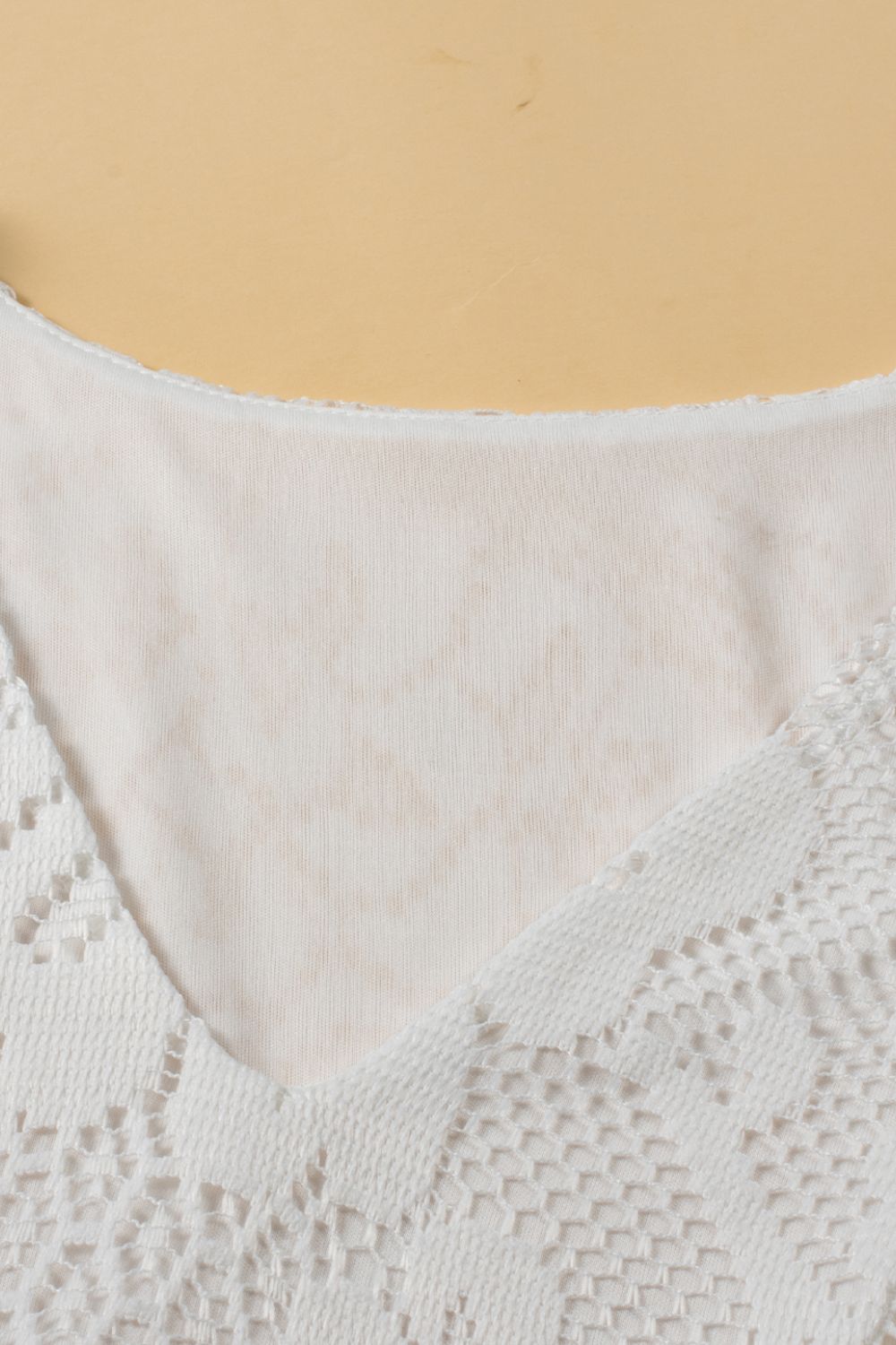 White lace peplum blouse with scalloped hem and V-neck detail.