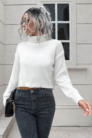White ribbed turtleneck sweater with scalloped hem detail and long sleeves.