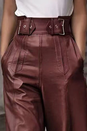 Burgundy wide-leg leather pants with a detailed buckle belt and pleated front.